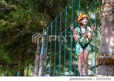 adventure climbing high wire park - people on course in mountain helmet and safety equipment adventure climbing high wire park - people on course in mountain helmet and safety equipment 95056385