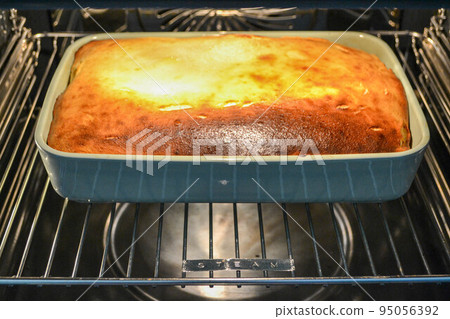 Cottage cheese casserole with raspberries and hazelnuts in a glass form is baked in the oven. Closeup. Cottage cheese casserole with raspberries and hazelnuts in a glass form is baked in the oven. Closeup. 95056392