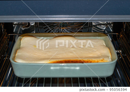 Cottage cheese casserole with raspberries and hazelnuts in a glass form is baked in the oven. Closeup. Cottage cheese casserole with raspberries and hazelnuts in a glass form is baked in the oven. Closeup. 95056394