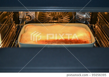 Cottage cheese casserole with raspberries and hazelnuts in a glass form is baked in the oven. Closeup. Cottage cheese casserole with raspberries and hazelnuts in a glass form is baked in the oven. Closeup. 95056395