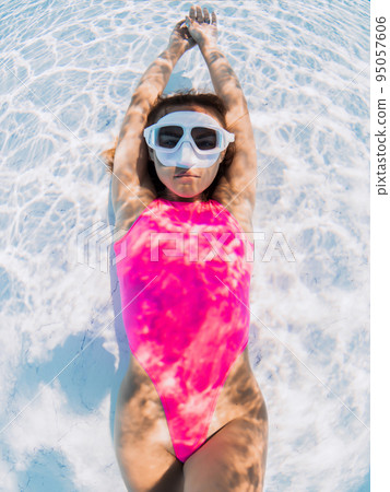 Beautiful woman in pink swimwear with diving mask posing underwater. Beautiful woman in pink swimwear with diving mask posing underwater. 95057606