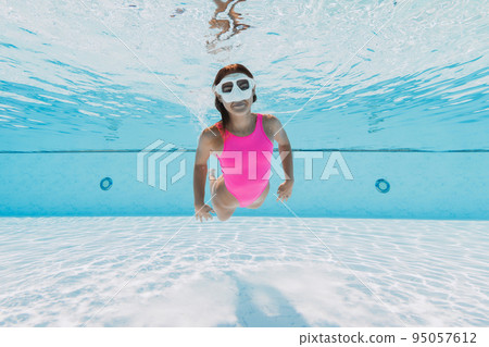Attractive woman in pink swimwear dive and swimming underwater in pool Attractive woman in pink swimwear dive and swimming underwater in pool 95057612