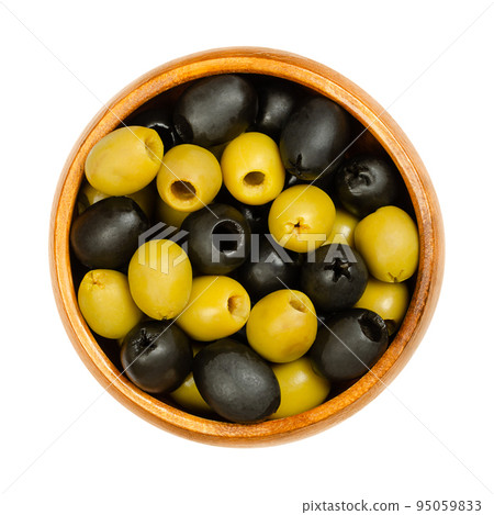 Pitted green and black olives, Hojiblanca, in a wooden bowl. European olives, Olea europaea, a cultivar from Lucena in Spain, mainly grown in Andalucia. Popular table olives with a lower oil content. 95059833