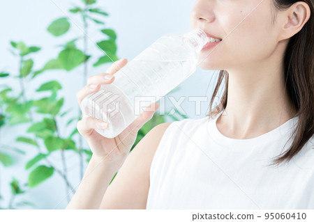 A young woman drinking water in a plastic bottle A young woman drinking water in a plastic bottle 95060410