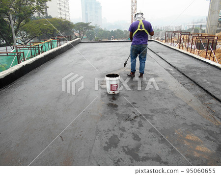 MELAKA, MALAYSIA -JULY 1, 2022: Waterproofing membrane applied by construction workers on top of the concrete slab. Waterproofing layer to prevent water from penetrating below the concrete slab.  95060655