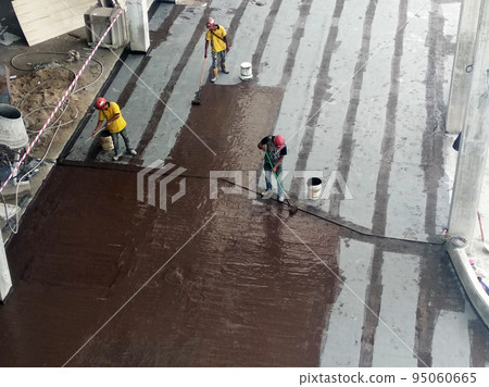 MELAKA, MALAYSIA -JULY 1, 2022: Waterproofing membrane applied by construction workers on top of the concrete slab. Waterproofing layer to prevent water from penetrating below the concrete slab. MELAKA, MALAYSIA -JULY 1, 2022: Waterproofing membrane applied by construction workers on top of the concrete slab. Waterproofing layer to prevent water from penetrating below the concrete slab. 95060665