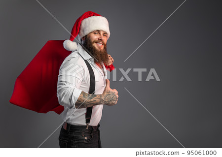 Christmas bearded smiling man in white shirt holds huge sack with presents gesturing thumbs up. Christmas bearded smiling man in white shirt holds huge sack with presents gesturing thumbs up. 95061000