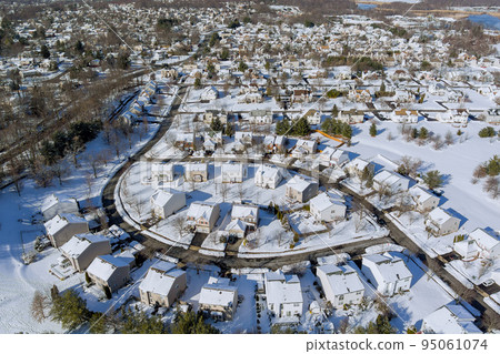 During a severe snowstorm that hit the area, there was snow on the roofs of many residential buildings in a small town in New Jersey that was surrounded by residential homes. 95061074