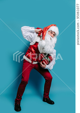 Full size of santa claus who sat down holding heavy sack of gifts on shoulder holds gift box in hand Full size of santa claus who sat down holding heavy sack of gifts on shoulder holds gift box in hand 95061077