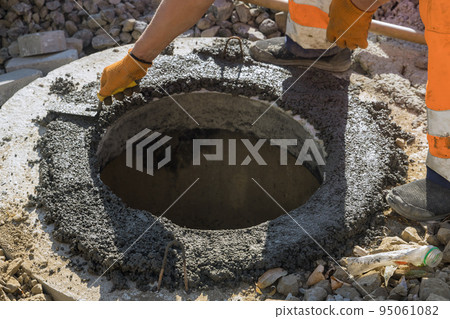 There is a utility worker who is constructing a pit for a septic tank the sewerage manhole, and reconstructing the sewage system 95061082