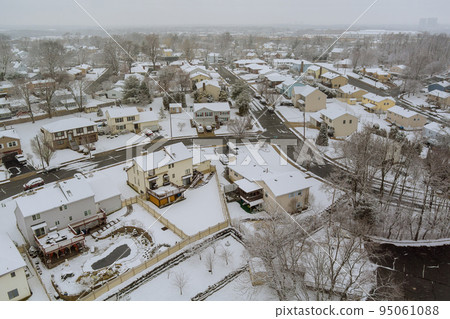 There is a small American town in New Jersey with a residential complex with a snowy roof during a winter snowfall when there is a snowstorm There is a small American town in New Jersey with a residential complex with a snowy roof during a winter snowfall when there is a snowstorm 95061088