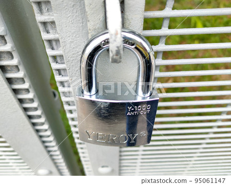JOHOR, MALAYSIA -AUGUST 1, 2022: Stainless steel pad lock is used to lock the gate. A rust-resistant type of pad lock is used for fences that are exposed to the weather. 95061147