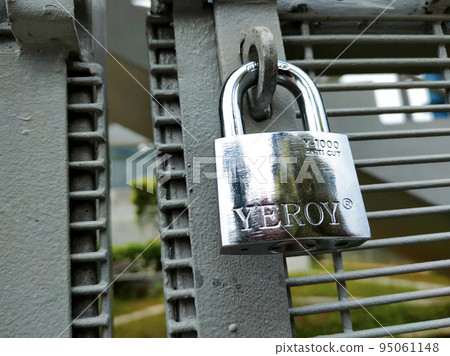 JOHOR, MALAYSIA -AUGUST 1, 2022: Stainless steel pad lock is used to lock the gate. A rust-resistant type of pad lock is used for fences that are exposed to the weather. JOHOR, MALAYSIA -AUGUST 1, 2022: Stainless steel pad lock is used to lock the gate. A rust-resistant type of pad lock is used for fences that are exposed to the weather. 95061148