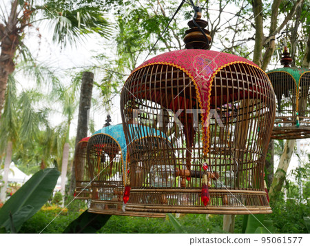 MELAKA, MALAYSIA -JUNE 7, 2022: Traditional bird cages made of bamboo are hung in an open area. Has a fabric cover to protect the bird inside from the weather. Displayed for exhibition. MELAKA, MALAYSIA -JUNE 7, 2022: Traditional bird cages made of bamboo are hung in an open area. Has a fabric cover to protect the bird inside from the weather. Displayed for exhibition. 95061577
