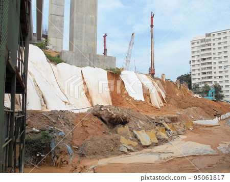 MELAKA, MALAYSIA - JULY 6, 2022: Slopes that have been cut, are temporarily covered using plastic or fabric for a while to prevent erosion caused by rainwater. This is as an immediate action. 95061817
