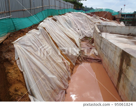 MELAKA, MALAYSIA - JULY 6, 2022: Slopes that have been cut, are temporarily covered using plastic or fabric for a while to prevent erosion caused by rainwater. This is as an immediate action. 95061824