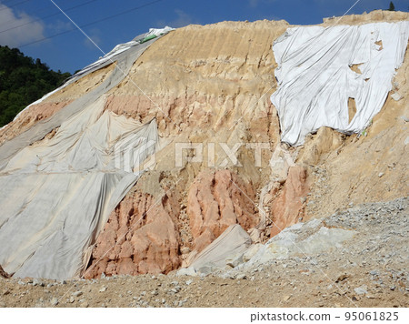 MELAKA, MALAYSIA - JULY 6, 2022: Slopes that have been cut, are temporarily covered using plastic or fabric for a while to prevent erosion caused by rainwater. This is as an immediate action. 95061825