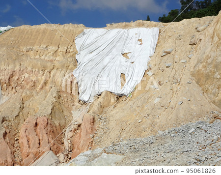 MELAKA, MALAYSIA - JULY 6, 2022: Slopes that have been cut, are temporarily covered using plastic or fabric for a while to prevent erosion caused by rainwater. This is as an immediate action. 95061826
