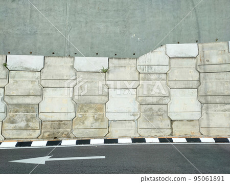 Precast concrete retaining wall panels are installed in layers as a retaining wall. This retaining wall functions to prevent erosion and also as a vertical dividing wall between two levels. Precast concrete retaining wall panels are installed in layers as a retaining wall. This retaining wall functions to prevent erosion and also as a vertical dividing wall between two levels. 95061891