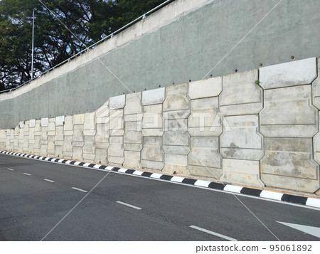 Precast concrete retaining wall panels are installed in layers as a retaining wall. This retaining wall functions to prevent erosion and also as a vertical dividing wall between two levels. 95061892