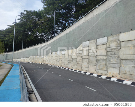 Precast concrete retaining wall panels are installed in layers as a retaining wall. This retaining wall functions to prevent erosion and also as a vertical dividing wall between two levels. 95061893