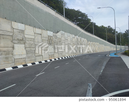 Precast concrete retaining wall panels are installed in layers as a retaining wall. This retaining wall functions to prevent erosion and also as a vertical dividing wall between two levels. 95061894