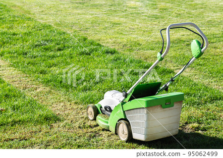 Lawn mover on green grass in summer garden 95062499