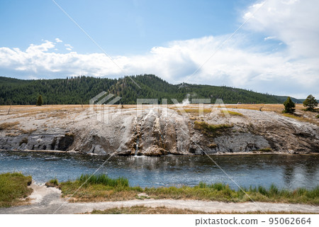 Beautiful view of Firehole River in Midway Geyser Basin. Water flowing by geothermal surface at Yellowstone park. Famous tourist attraction with sky in background. Beautiful view of Firehole River in Midway Geyser Basin. Water flowing by geothermal surface at Yellowstone park. Famous tourist attraction with sky in background. 95062664