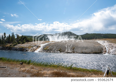 Scenic view of Firehole River in Midway Geyser Basin with sky in background. Water flowing by geothermal landscape at famous Yellowstone national park. Tourist sightseeing attraction during summer. Scenic view of Firehole River in Midway Geyser Basin with sky in background. Water flowing by geothermal landscape at famous Yellowstone national park. Tourist sightseeing attraction during summer. 95062674