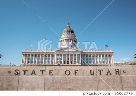 Flags waving at State Capitol building in Salt Lake city. Low angle view of government built structure with clear blue sky in background. Famous landmark in city during sunny day. 95062779