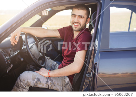 Happy brunet male drives his new car, sits - Stock Photo 