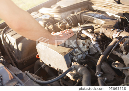 Faceless man touches engine of his car, has some problems, can not drive automobile, needs new spare parts, parks machine on side of road, tries to repair his auto. Driving and travelling concept. Faceless man touches engine of his car, has some problems, can not drive automobile, needs new spare parts, parks machine on side of road, tries to repair his auto. Driving and travelling concept. 95063318