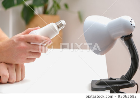 The man changes the lamp. Energy-saving lamp 95063682