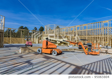 It is a contractor using a boom truck forklift at a construction site where the framing beams for the new home that is under construction are being installed. It is a contractor using a boom truck forklift at a construction site where the framing beams for the new home that is under construction are being installed. 95063804
