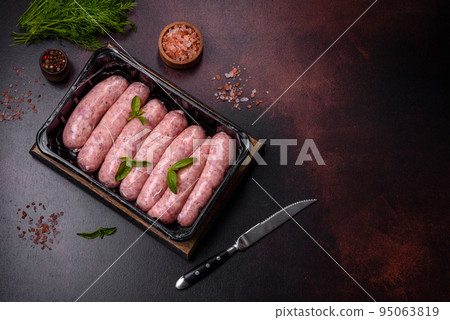 Raw sausages with ingredients on a cutting board on a dark concrete background with copy space Raw sausages with ingredients on a cutting board on a dark concrete background with copy space 95063819