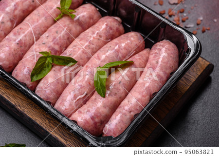 Raw sausages with ingredients on a cutting board on a dark concrete background with copy space Raw sausages with ingredients on a cutting board on a dark concrete background with copy space 95063821