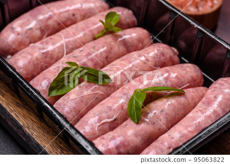 Raw sausages with ingredients on a cutting board on a dark concrete background with copy space Raw sausages with ingredients on a cutting board on a dark concrete background with copy space 95063822