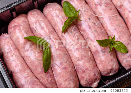 Raw sausages with ingredients on a cutting board on a dark concrete background with copy space Raw sausages with ingredients on a cutting board on a dark concrete background with copy space 95063823