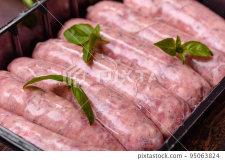 Raw sausages with ingredients on a cutting board on a dark concrete background with copy space Raw sausages with ingredients on a cutting board on a dark concrete background with copy space 95063824