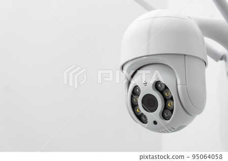 Round CCTV camera with antennas shoots video on the white wall. Digital equipment to record and broadcast real time video closeup 95064058