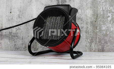 Heater for the apartment, closeup. Electric halogen fan heater on floor. Heat gun with a fan for heating.  95064105
