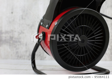 Heater for the apartment, closeup. Electric halogen fan heater on floor. Heat gun with a fan for heating. Heater for the apartment, closeup. Electric halogen fan heater on floor. Heat gun with a fan for heating. 95064111