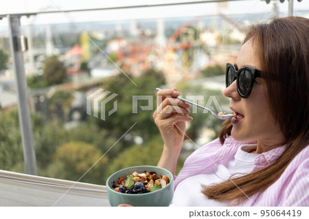 young woman eating chia pudding with nuts and berries young woman eating chia pudding with nuts and berries 95064419