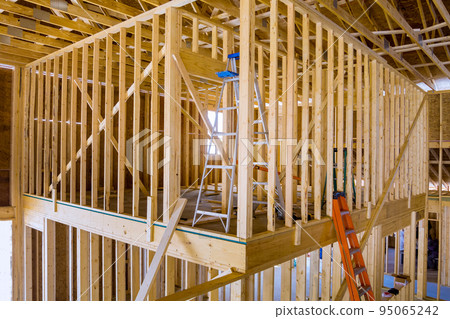 Building frame for a new residential building while it is still under construction with beams fenestrations on a construction site 95065242