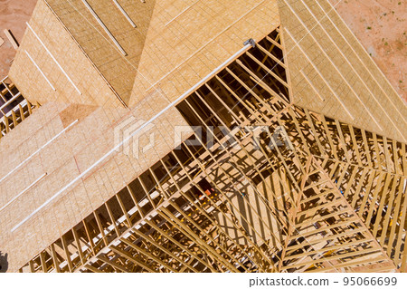 Under construction newly constructed house with roof truss system beams and wooden frame that is in the process of being constructed 95066699