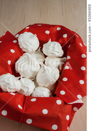 Small meringues meringue on a red background Small meringues meringue on a red background 95066909