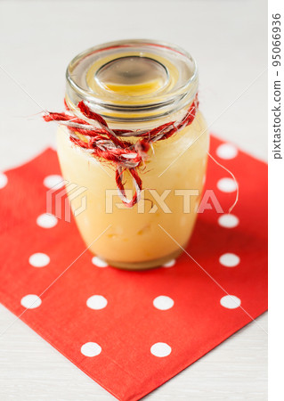 Lemon cream in a glass jar stands on a napkin Lemon cream in a glass jar stands on a napkin 95066936