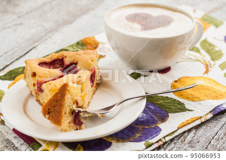 pie with plums and slice and cup with coffee 95066953