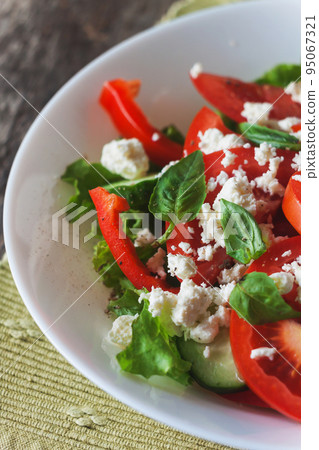 Shopska salad in a white plate on a wooden background, close-up Shopska salad in a white plate on a wooden background, close-up 95067321