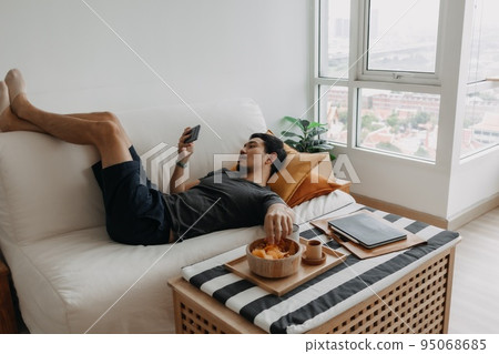 Man watch online tv and eating snack instead of working from home. Man watch online tv and eating snack instead of working from home. 95068685